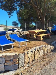 two blue chairs and a picnic table and a stone wall at Cottage Vittoria in Marazzino