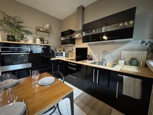 a kitchen with black cabinets and a wooden table at The Light Downtown - 9 pers - 24h du Mans - Rêve au Mans in Le Mans