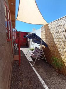 a table and a chair under a blue umbrella at Desert Wings in San Pedro de Atacama