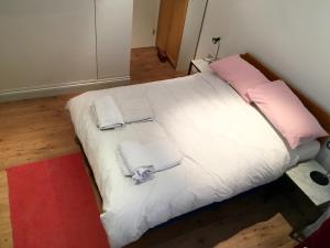 a white bed with two towels and pink pillows at Edencourt Apartment in London