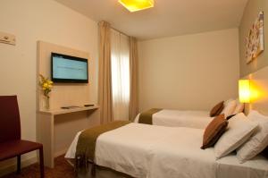 a hotel room with two beds and a flat screen tv at Hotel De Los Andes in Ushuaia