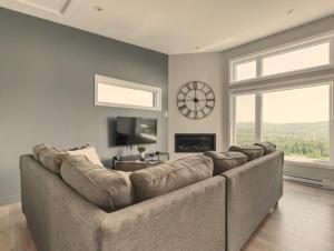 eine große Couch in einem Wohnzimmer mit einer Uhr an der Wand in der Unterkunft Condo Matha in Saint-Jean-de-Matha