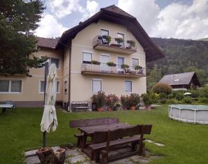 a house with an umbrella and a table and a bench at FeWo Schätzer - Geiger in Bodensdorf