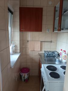 Una pequeña cocina con estufa y fregadero. en City apartmant, en Tuzla