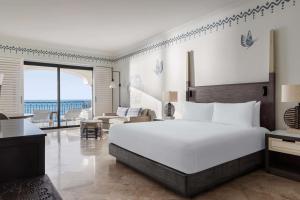 a bedroom with a large white bed and a living room at Hilton Los Cabos in San José del Cabo +56 photos