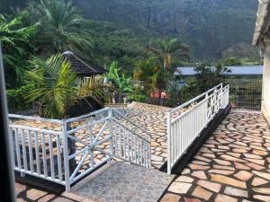 a white gate on a stone walkway with mountains in the background at La Villa du Sculpteur Palmiste Rouge Cilaos, maison entière in Cilaos
