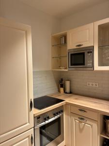 a kitchen with white cabinets and a microwave at Zentrales Panorama-Apartment über den Dächern am Meranplatz - Terrasse und Top Lage in Bad Aussee