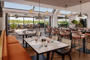 维也纳Hilton Vienna Waterfront的有桌椅和酒吧的餐厅
