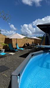 a swimming pool with chairs and tables and umbrellas at La Maison Caraïbes in Sainte-Anne