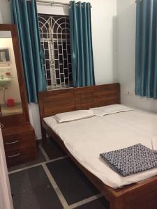 a bedroom with a bed and a window with green curtains at Vaishali bungalow Nagaon in Nagaon