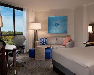 a hotel room with a bed and a couch and a desk at Hilton Orlando Buena Vista Palace - Disney Springs Area in Orlando