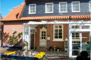 a brick house with a white pergola at Fehmarn Bauernhauskunz in Fehmarn
