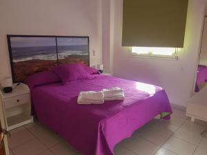a purple bed with two towels on top of it at EL HOGAR DEL MAGEC in Las Palmas de Gran Canaria