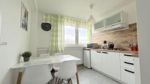 a kitchen with white cabinets and a table and chairs at Apartament KOREK in Stronie Śląskie
