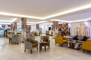 a lobby of a hotel with yellow chairs and tables at The Palace Hotel Suites in Khamis Mushayt