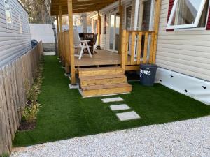 eine Veranda eines Hauses mit einer Terrasse und Gras in der Unterkunft Mobilhome bord de mer in Le Grau-dʼAgde
