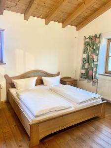 a bedroom with a large bed with white sheets at Landhaus Maiergschwendt inkl Chiemgaukarte in Ruhpolding