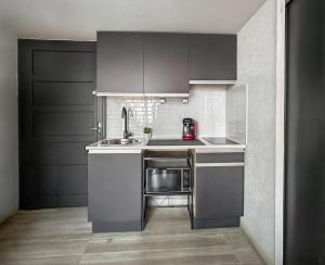 a small kitchen with a sink and a microwave at T2 lumineux & paisible à quelques pas du sable fin in Le Barcarès +10 photos