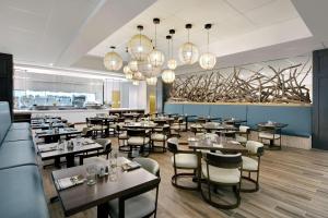 圣奥古斯丁海滩Embassy Suites St Augustine Beach Oceanfront Resort的有桌椅和吊灯的餐厅