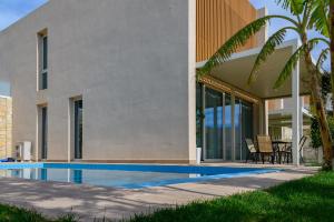 a villa with a swimming pool in front of a house at MIKU Green Coast in Palasë