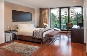 a bedroom with a bed and a desk and a window at Hotel Jazz Apartments in Bogotá