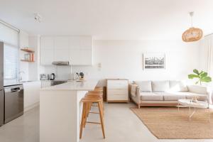 a white kitchen and living room with a couch at 1 Bedroom Muizenberg Beach Apartment with Pool and Mountain Views in Muizenberg