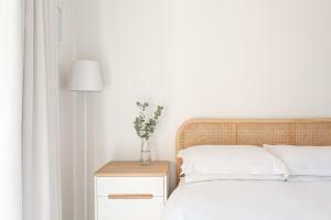 a bedroom with a bed and a nightstand with a vase on it at 1 Bedroom Muizenberg Beach Apartment with Pool and Mountain Views in Muizenberg