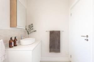 a white bathroom with a sink and a mirror at 1 Bedroom Muizenberg Beach Apartment with Pool and Mountain Views in Muizenberg +7 photos