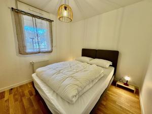 a bedroom with a large bed with white sheets and a window at Appartement 4 à 5 personnes au bord du lac in Génos +14 photos