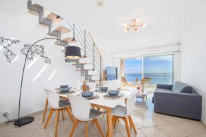 a living room with a table and chairs and a staircase at JARDINS DE MONACO - Vue Mer - Jacuzzi - Parking in Cap d'Ail