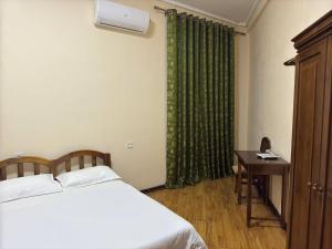 a bedroom with a bed and a table and a green curtain at Hotel Malika Tashkent in Tashkent +18 photos