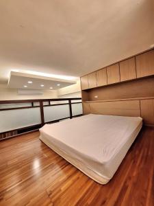 ein großes Bett in einem Zimmer mit Holzboden in der Unterkunft Cafe溫泉屋 in Jiaoxi