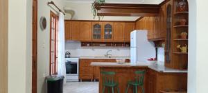 a kitchen with wooden cabinets and green bar stools at Tria Liodendra Corfu - Sea in Petrití +38 photos