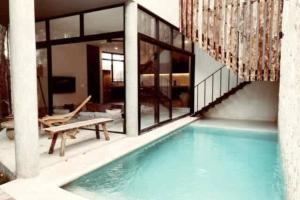 a house with a swimming pool next to a building at Boho Jungle Villa -Pvt Pool -Concierge-Hammock 7B in Tulum