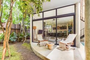 a patio with two chairs and a table and windows at Boho Jungle Villa -Pvt Pool -Concierge-Hammock 7B in Tulum