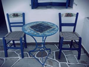 Dos sillas y una mesa con una pizza. en Romanza, en Cherronisos