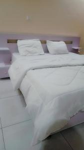 1 cama blanca grande con sábanas y almohadas blancas en KIGALi LODGE APART, en Kigali