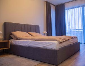 a bed in a bedroom with a large window at Mint Vibe Apartment in Odorheiu Secuiesc