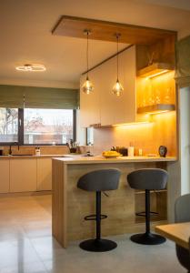 a kitchen with two bar stools at a counter at Mint Vibe Apartment in Odorheiu Secuiesc