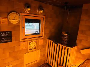 a room with a tv and clocks on the wall at Dormy Inn Express Koriyama in Koriyama