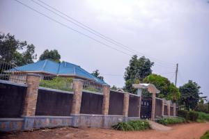 a house with a fence and a blue roof at Doreens Villa in Wakiso