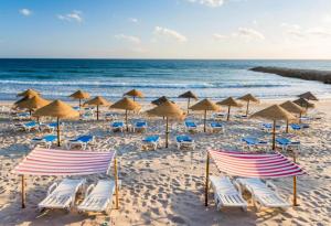 a group of chairs and umbrellas on a beach at Front Beach Costa Caparica Lisbon in Costa da Caparica