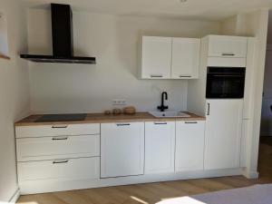 a white kitchen with white cabinets and a stove at De oude brouwerij in Reusel