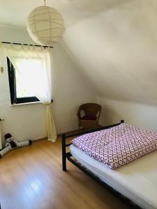 a bedroom with a bed and a chair and a window at Ferienhaus Thalblick in Ruhla in Ruhla