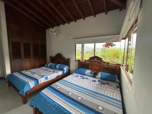 two beds in a room with a window at Cabaña La Isabelita in Chinácota