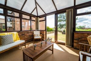 ein Wintergarten mit Couch, Tisch und Fenstern in der Unterkunft Morea Cottage - 2 Bed - Hot tub in Horning + 34 Fotos