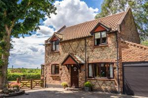 ein Steinhaus mit einer Garage und einem Zaun in der Unterkunft Morea Cottage - 2 Bed - Hot tub in Horning