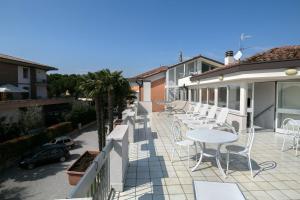 eine Terrasse mit weißen Stühlen und einem Tisch auf dem Balkon in der Unterkunft Hotel Olimpia in Sirmione