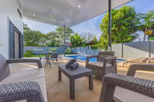 a patio with chairs and a table and a pool at CASA SERENITY , brand new house, walk 2 beach, private pool, wifi, PURA VIDA!!!! in Uvita