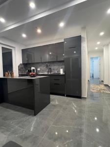 a kitchen with black cabinets and a tile floor at Skyline View Apartment in Ulcinj